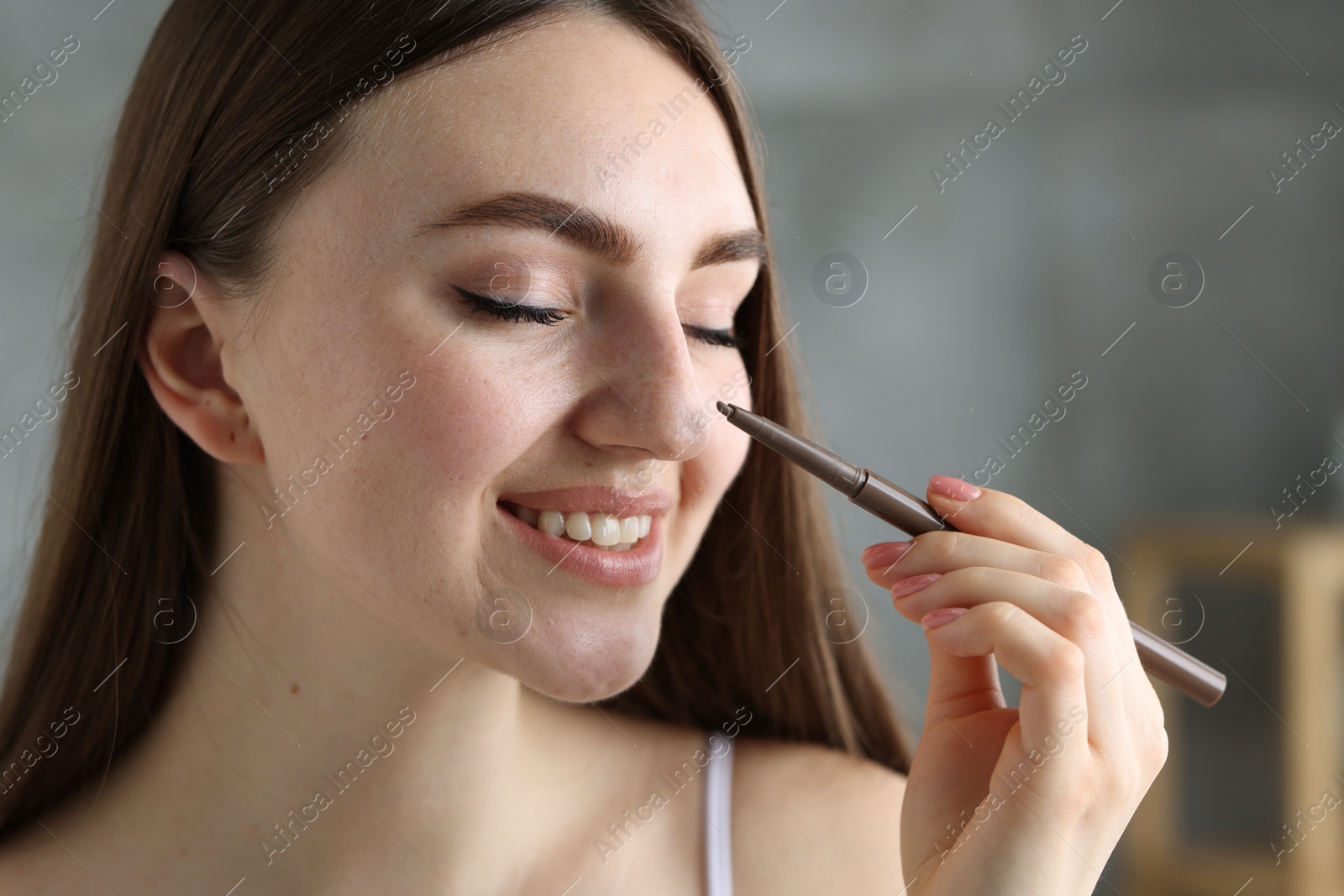 Photo of Smiling woman drawing freckles with pen indoors, closeup