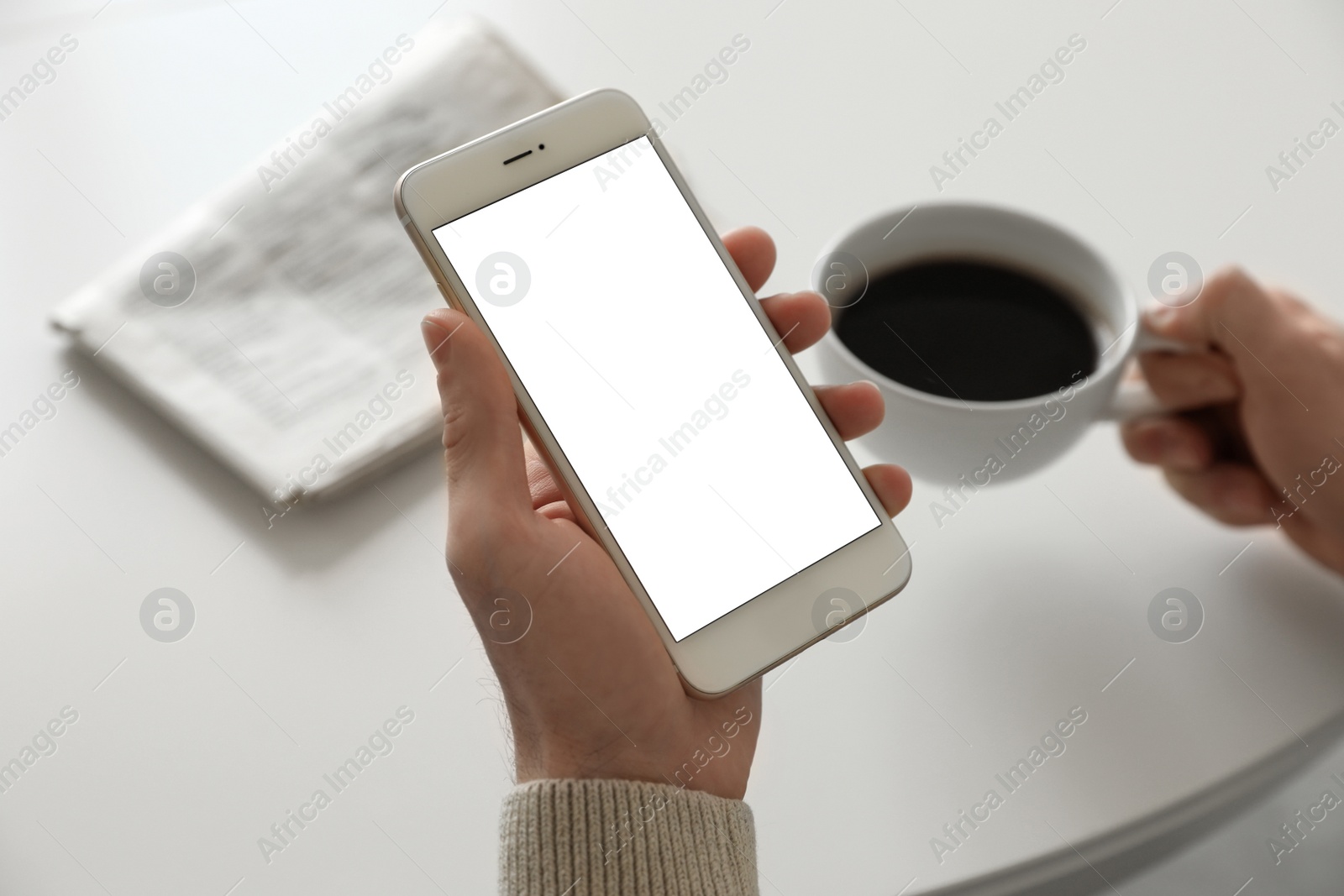 Image of Man holding mobile phone with empty screen at table, closeup