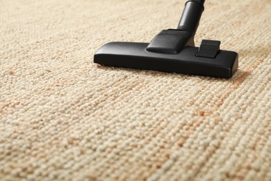 Photo of Removing dirt from beige carpet with modern vacuum cleaner, closeup. Space for text