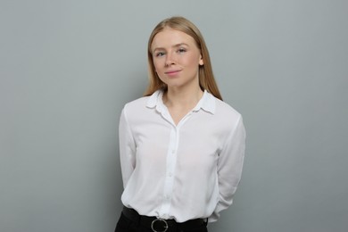 Portrait of beautiful young woman in white shirt on grey background