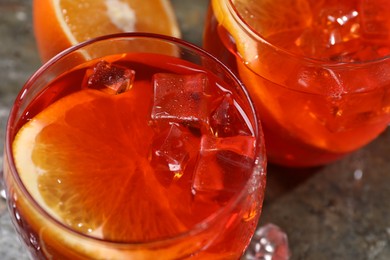 Photo of Aperol spritz cocktail, ice cubes and orange slices in glasses on table, closeup