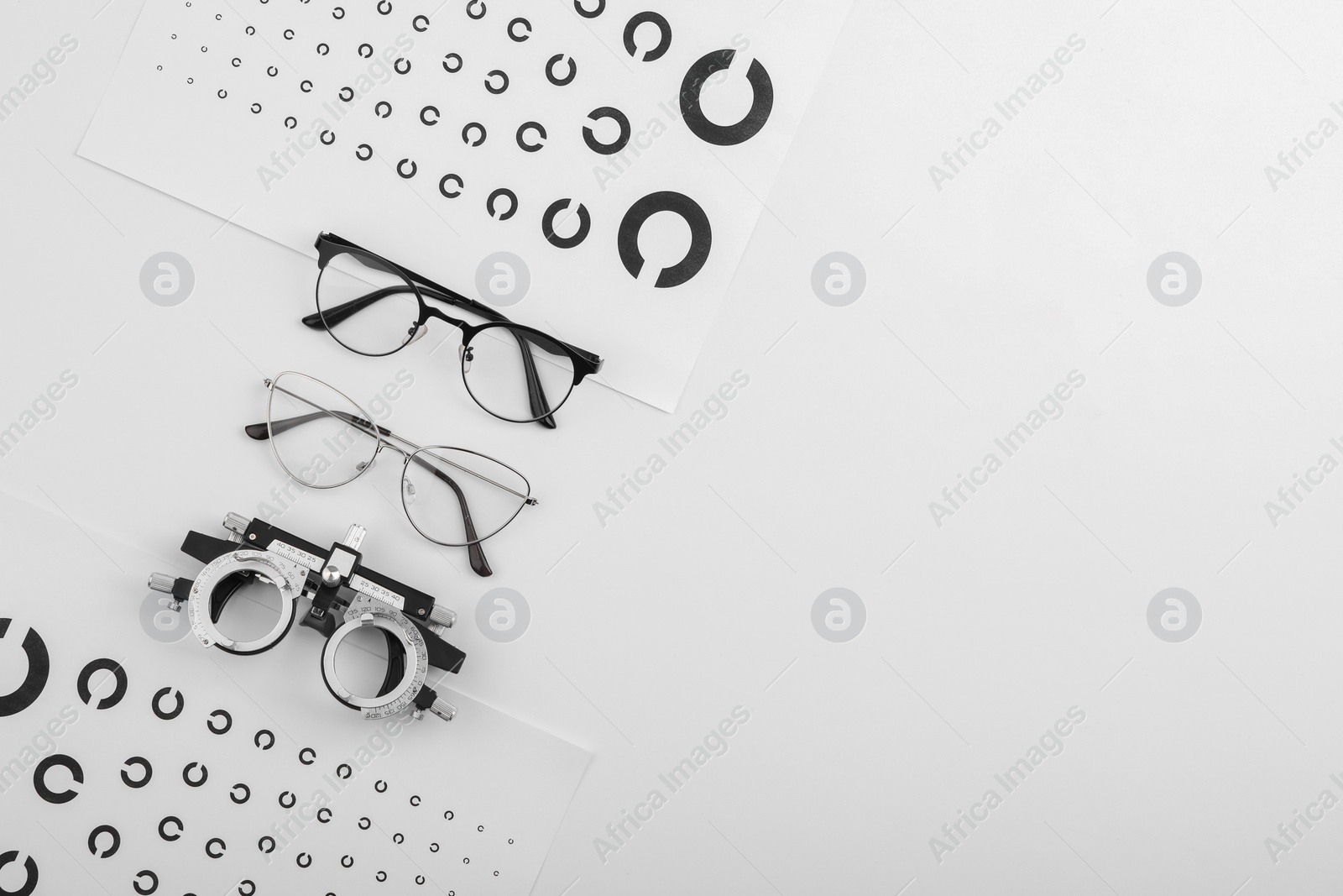 Photo of Vision test charts, glasses and trial frame on white background, flat lay. Space for text