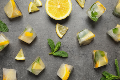 Flat lay composition with fresh juicy lemon, mint and ice cubes on grey table