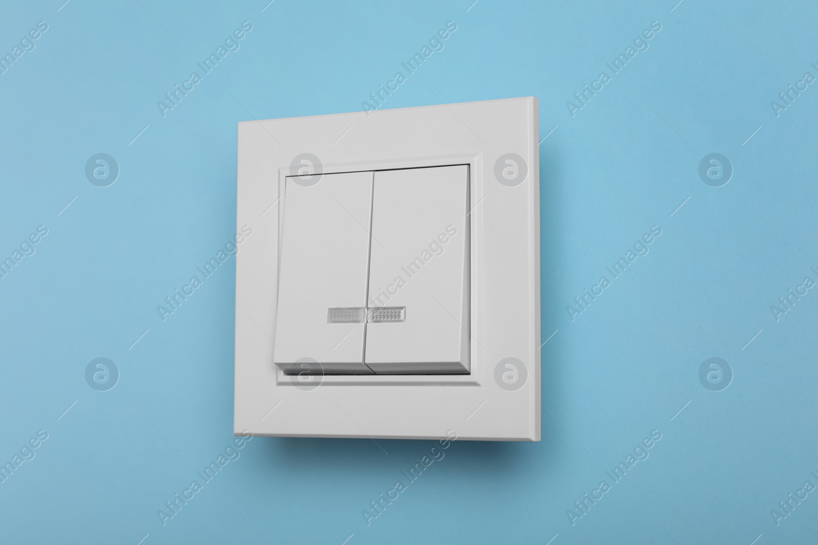 Photo of White plastic light switch on turquoise background