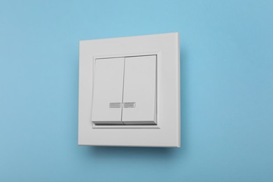 Photo of White plastic light switch on turquoise background