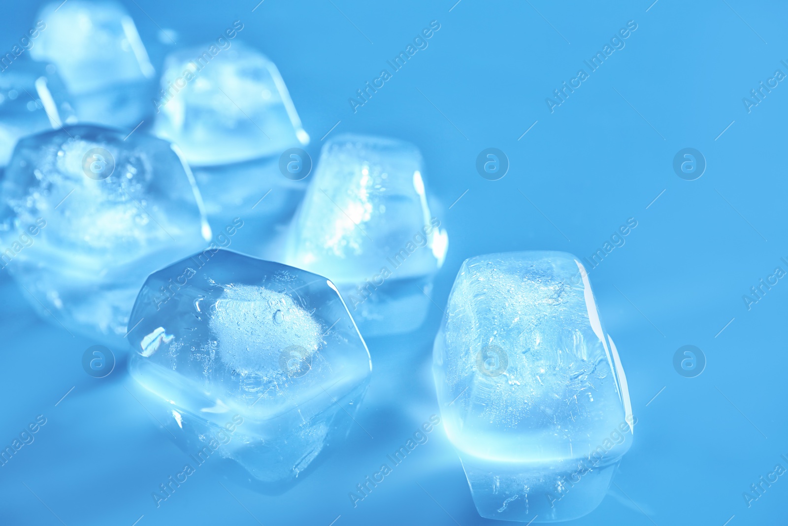 Photo of Transparent ice cubes on color mirror surface