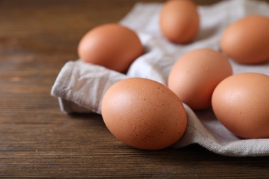 Photo of Raw brown chicken eggs on wooden table, closeup