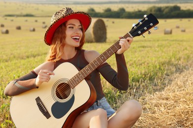 Photo of Beautiful happy hippie woman playing guitar in field