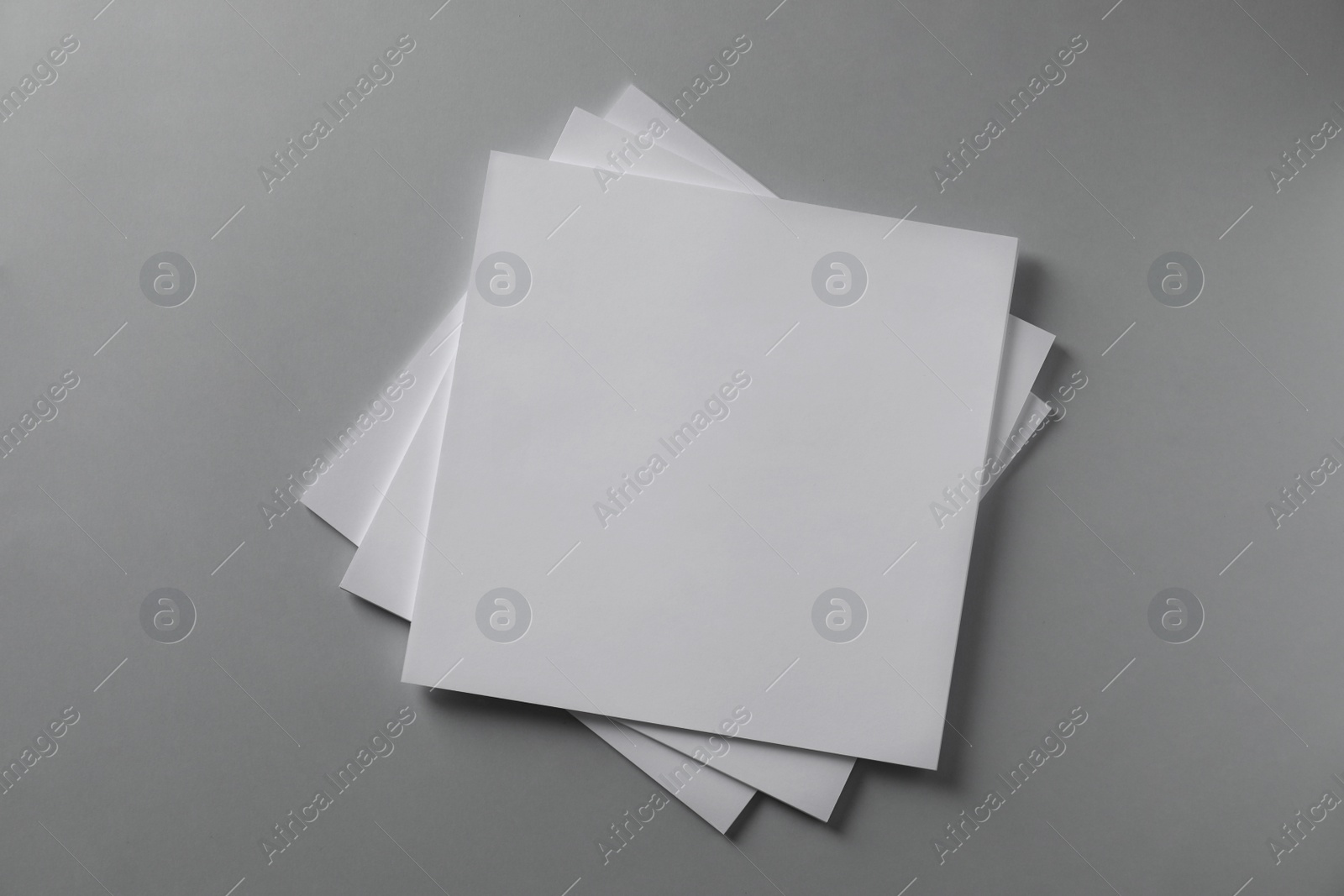 Photo of Stack of blank paper sheets for brochure on light grey background, top view