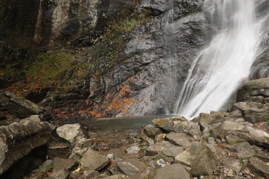 Picturesque view of beautiful mountain waterfall and rocks outdoors