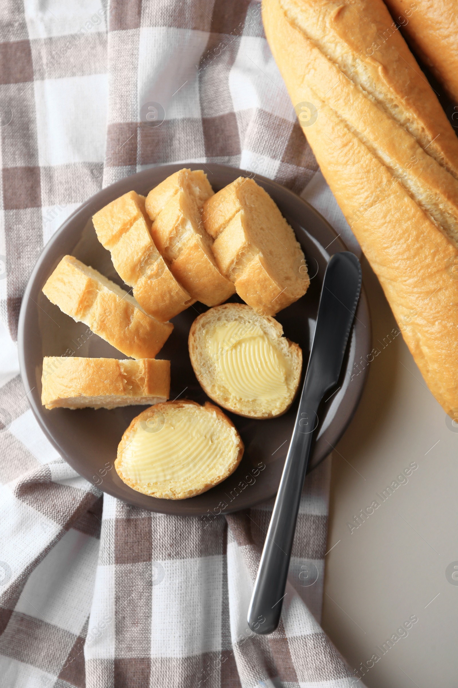 Photo of Whole and cut baguettes with fresh butter on table, flat lay