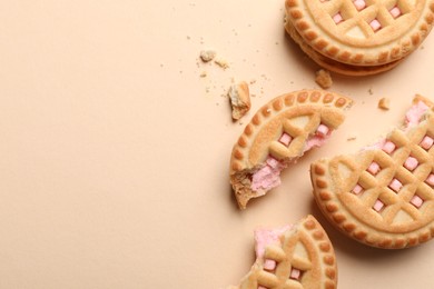 Photo of Tasty sandwich cookies with cream on beige background, flat lay. Space for text