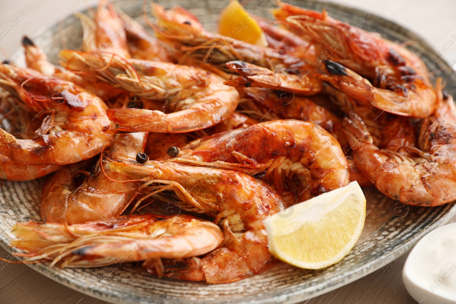 Photo of Delicious cooked shrimps served with lemon on plate, closeup