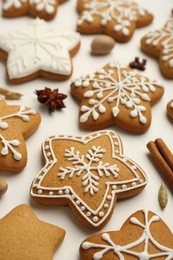 Photo of Tasty Christmas cookies with icing and spices on white background, closeup