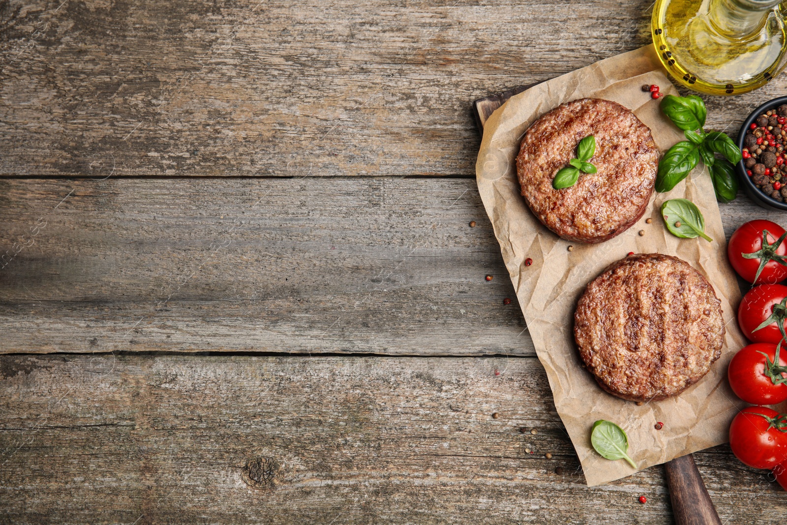 Photo of Tasty grilled hamburger patties with cherry tomatoes and seasonings on wooden table, flat lay. Space for text