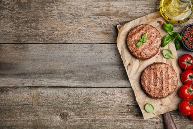 Photo of Tasty grilled hamburger patties with cherry tomatoes and seasonings on wooden table, flat lay. Space for text