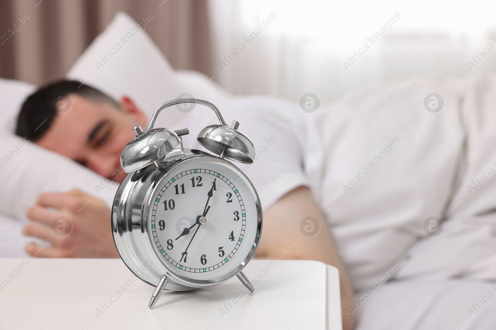 Photo of Man sleeping in bedroom, focus on alarm clock. Space for text