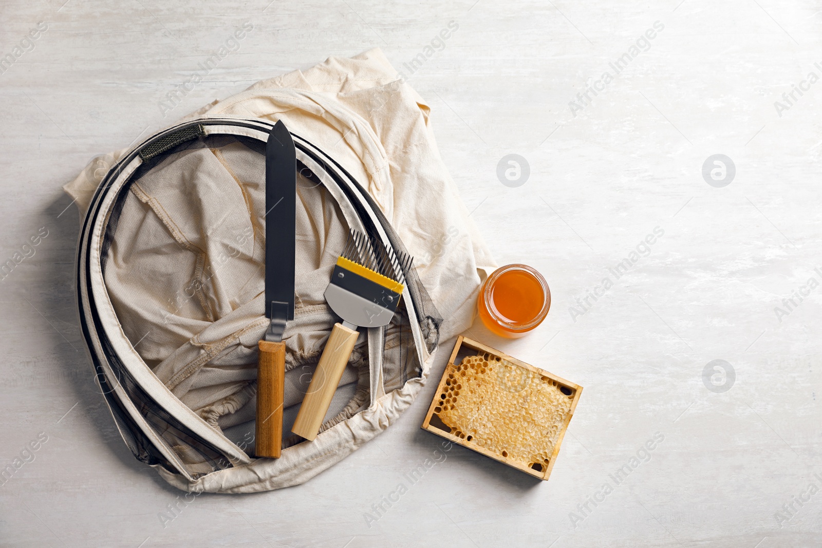 Photo of Different beekeeping tools and jar of honey on white table, flat lay. Space for text