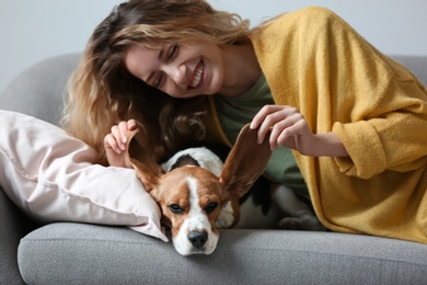 Young woman with her dog resting on sofa at home