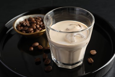Coffee cream liqueur in glass and beans on table, closeup