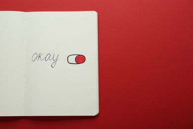 Photo of Notebook with word Okay and drawing of switch on button against red background, top view. Space for text