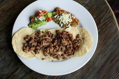 Photo of Plate with delicious tacos served on wooden table, top view