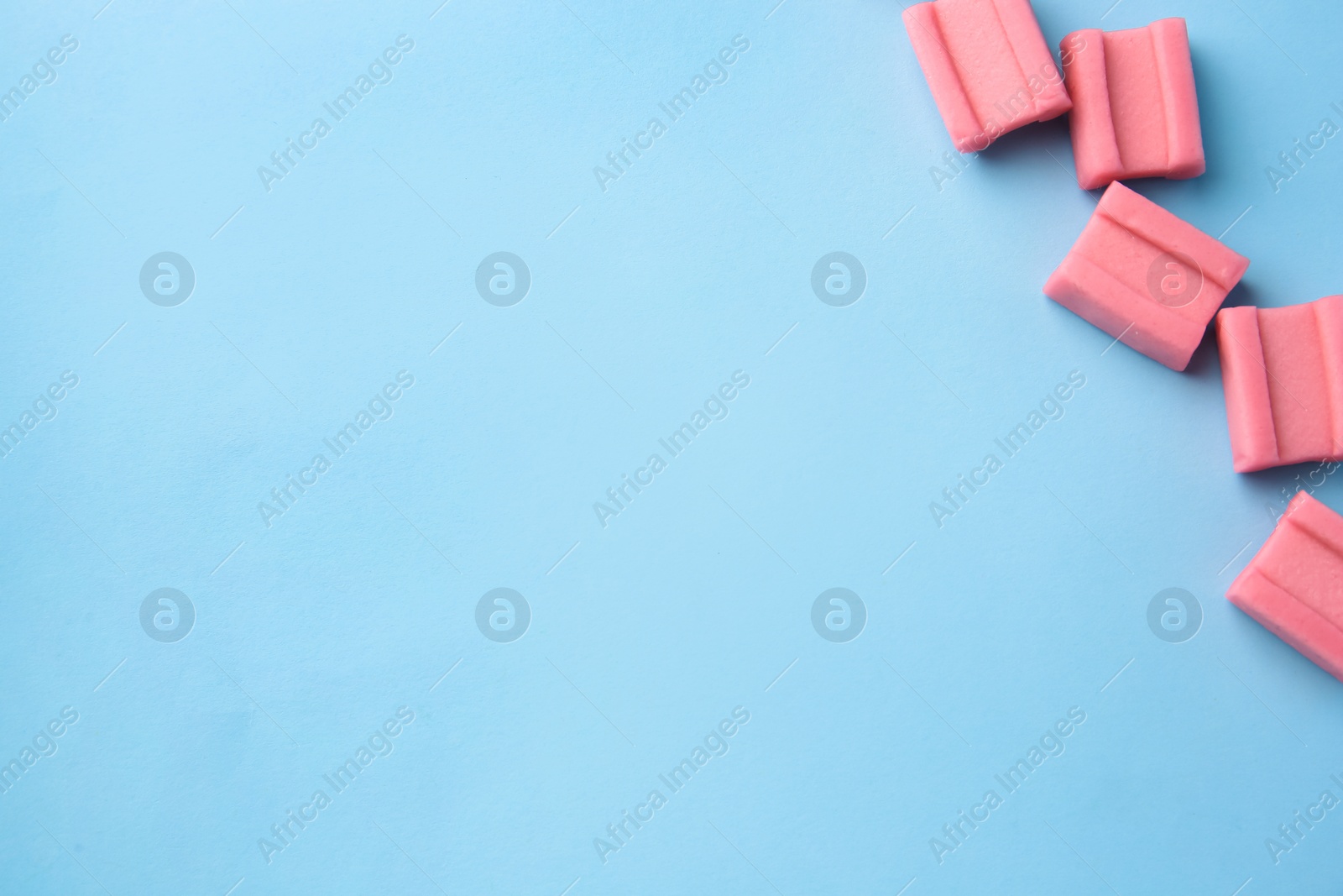 Photo of Tasty chewing gums on light blue background, flat lay. Space for text