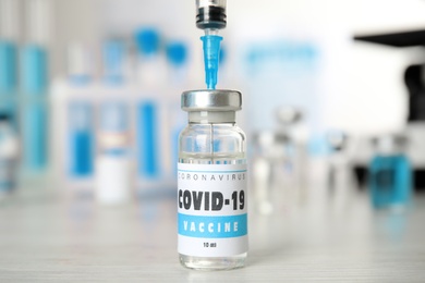 Filling syringe with vaccine against Covid-19 on white table