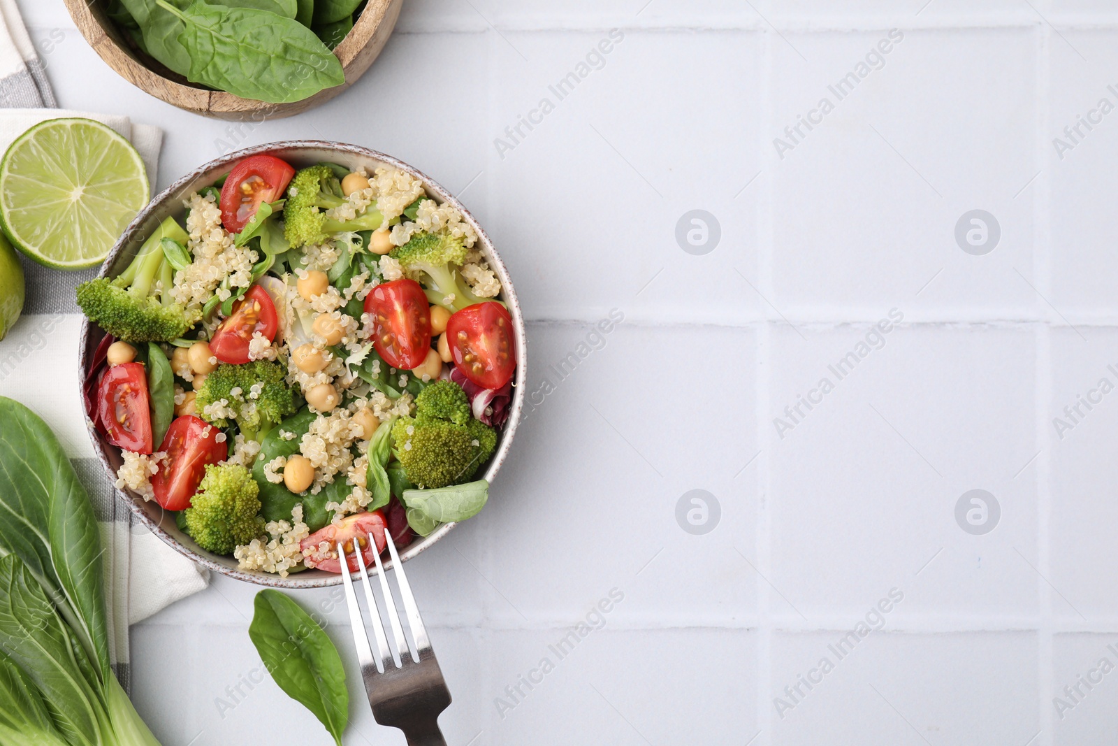 Photo of Healthy meal. Tasty salad with quinoa, chickpeas and vegetables served on white tiled table, flat lay with space for text