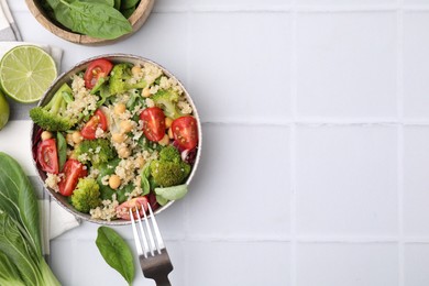 Photo of Healthy meal. Tasty salad with quinoa, chickpeas and vegetables served on white tiled table, flat lay with space for text