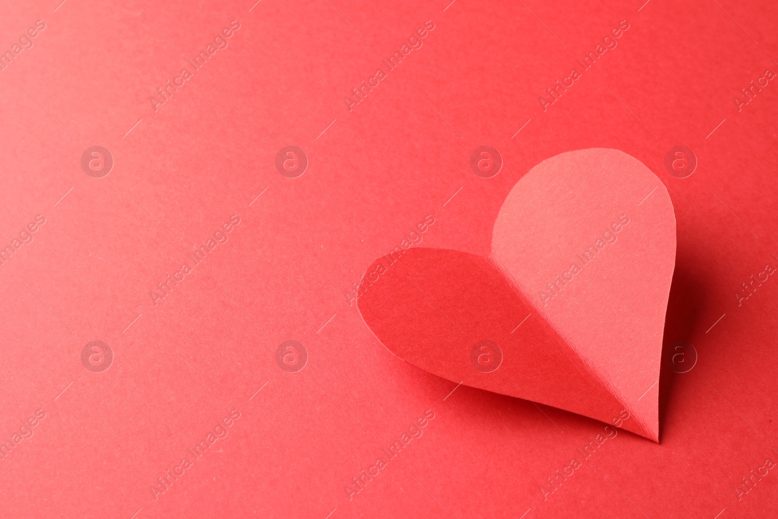 Photo of One paper heart on red background. Space for text