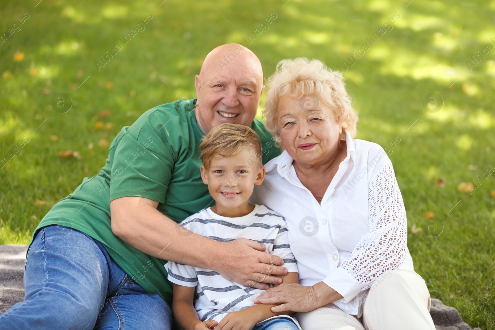 Photo of Happy elderly couple with grandson in park