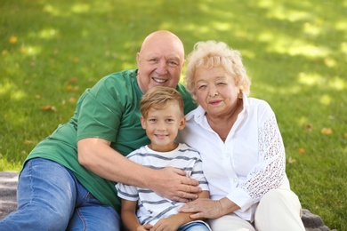 Happy elderly couple with grandson in park