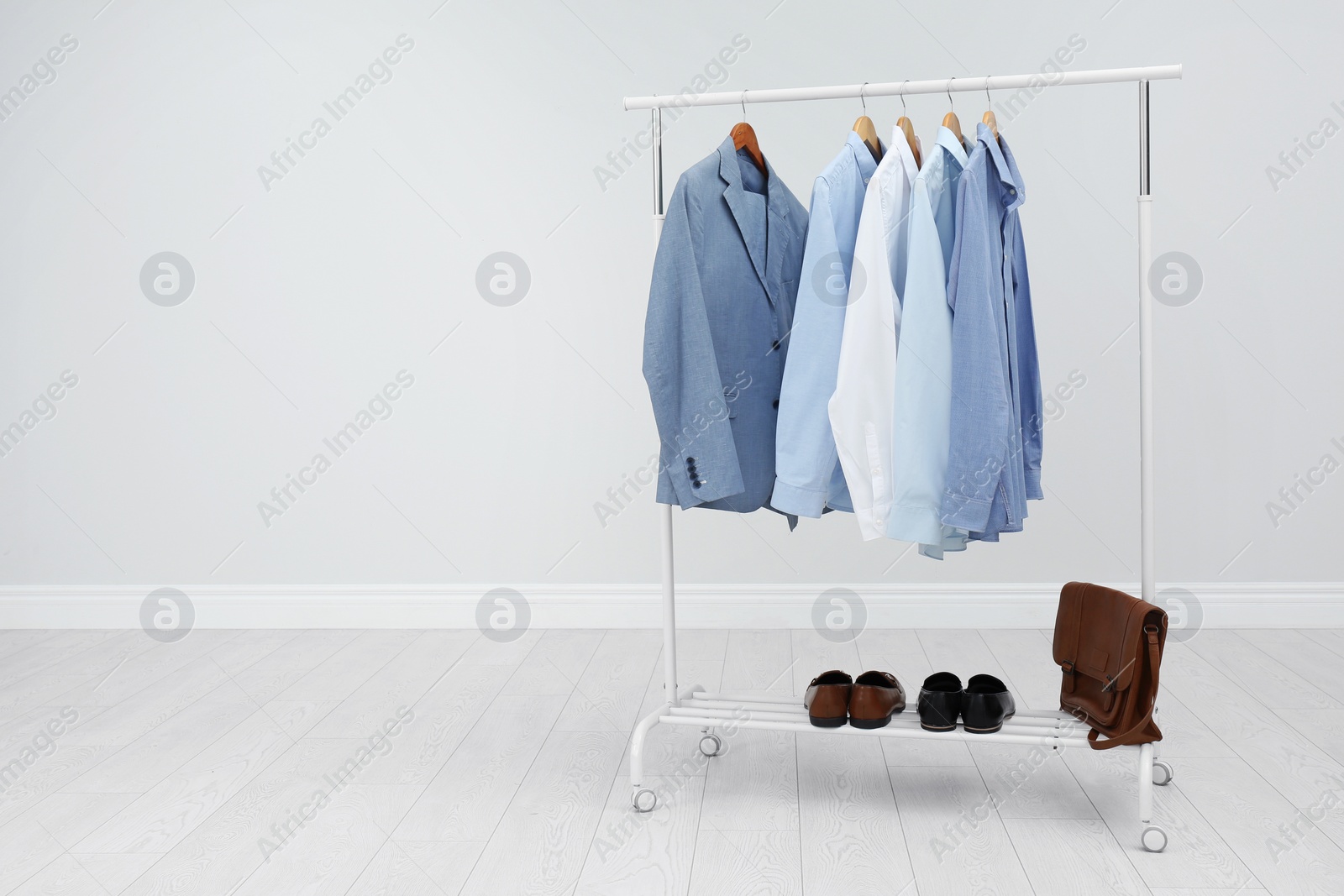 Photo of Rack with stylish men's clothes in room. Space for text