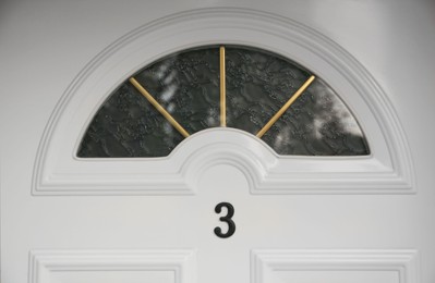 House number three on white wooden door