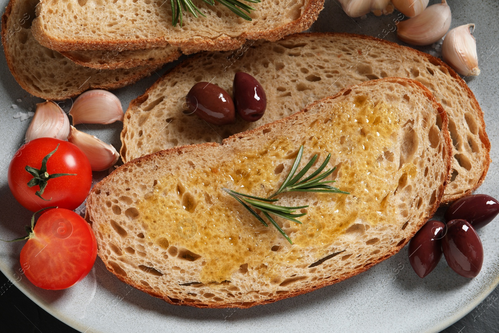 Photo of Tasty bruschettas with oil and rosemary on plate, top view