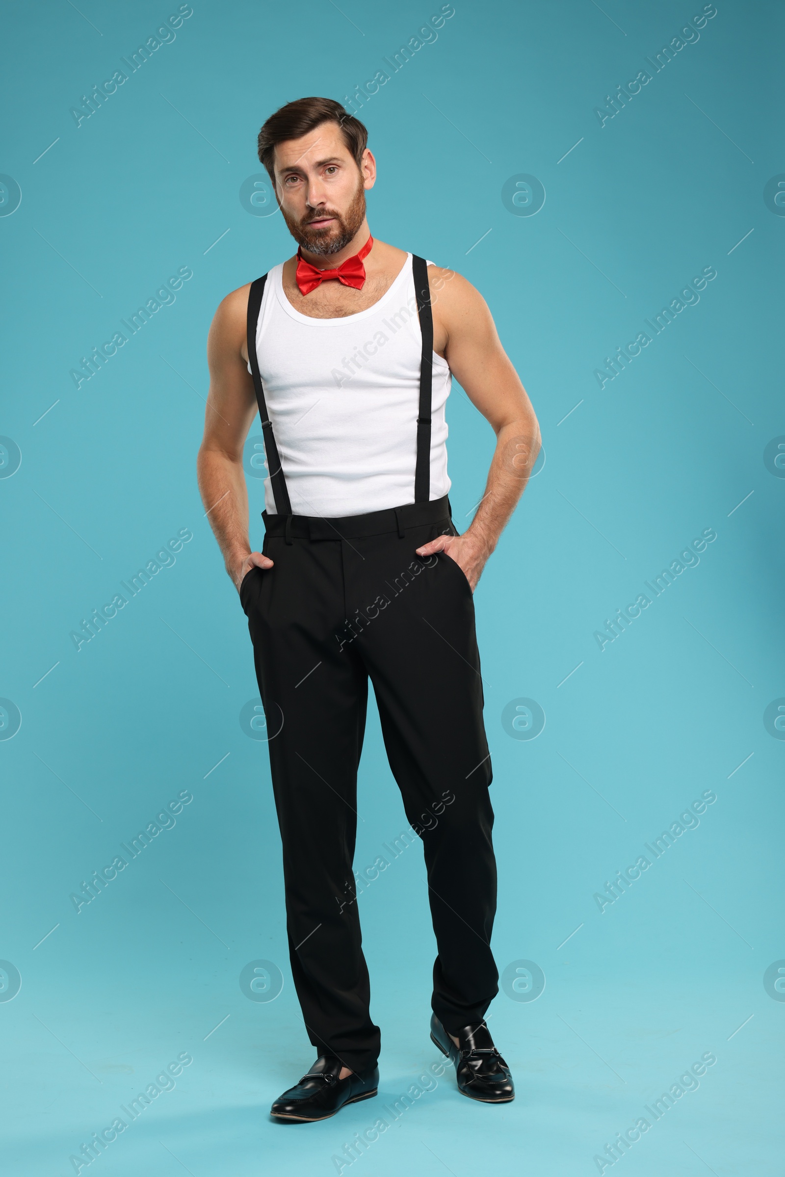 Photo of Attractive man with red bow tie posing on light blue background