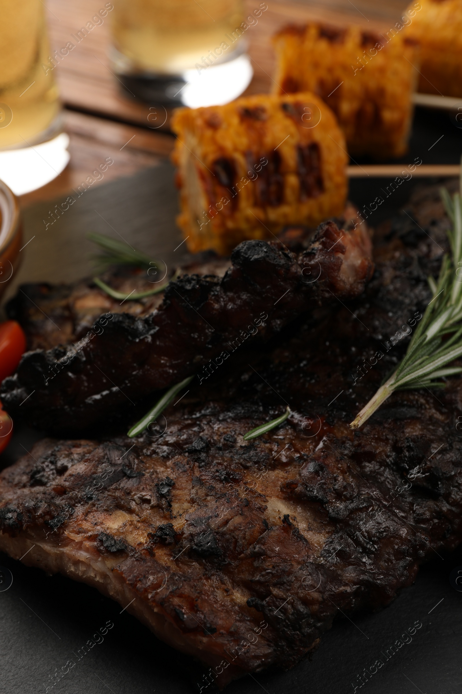 Photo of Delicious grilled ribs and corn on table, closeup view