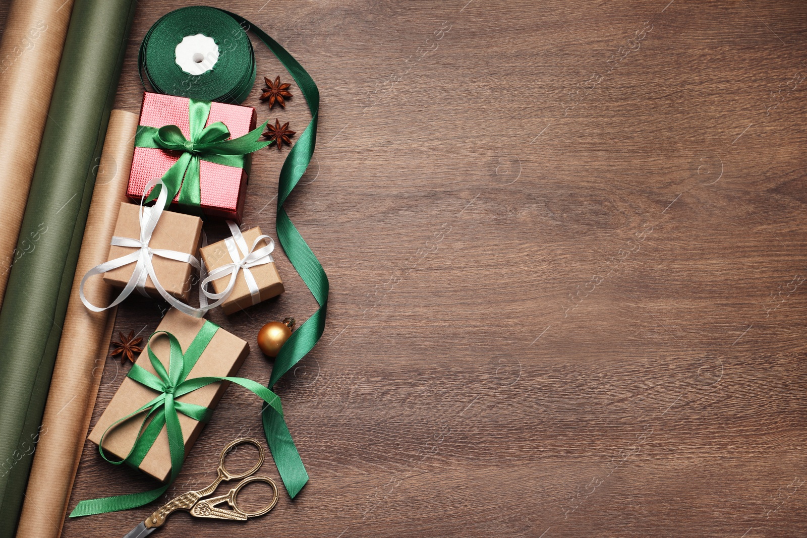 Photo of Flat lay composition with beautiful Christmas gift boxes and wrapping paper on wooden table. Space for text