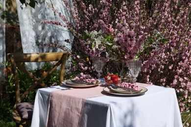 Stylish table setting with beautiful spring flowers in garden