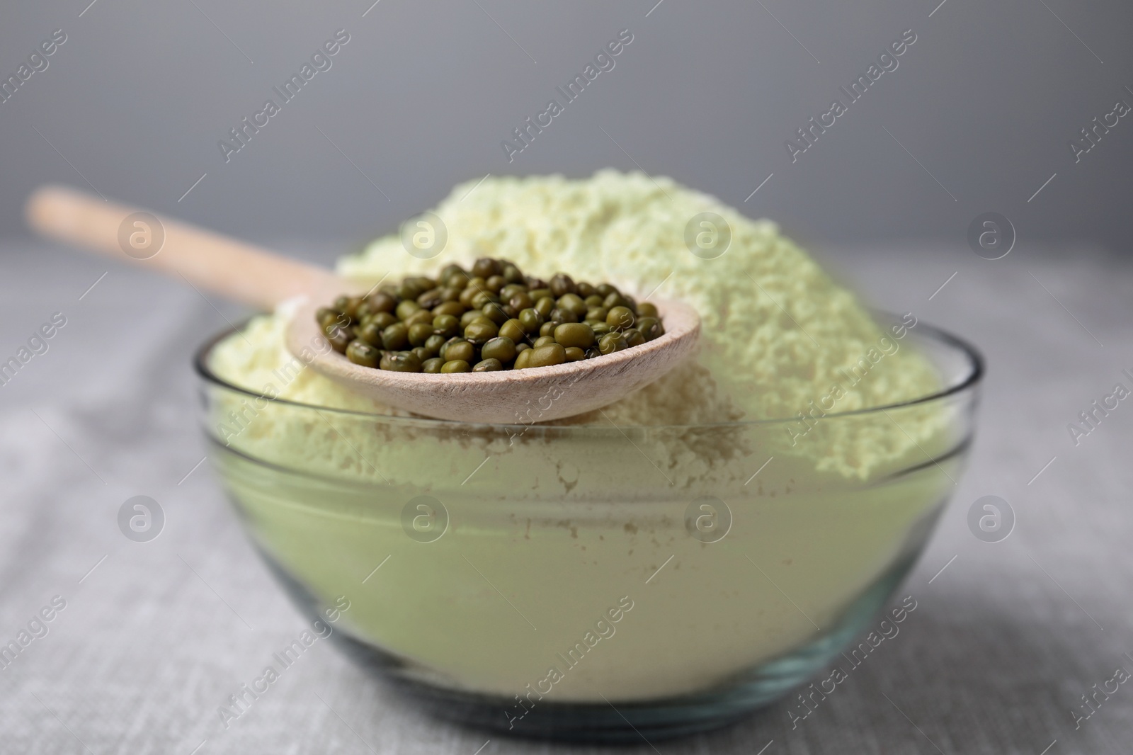 Photo of Bowl of flour and spoon with mung beans on light grey table