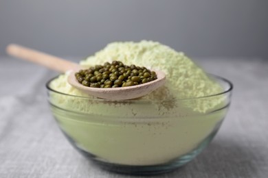 Photo of Bowl of flour and spoon with mung beans on light grey table