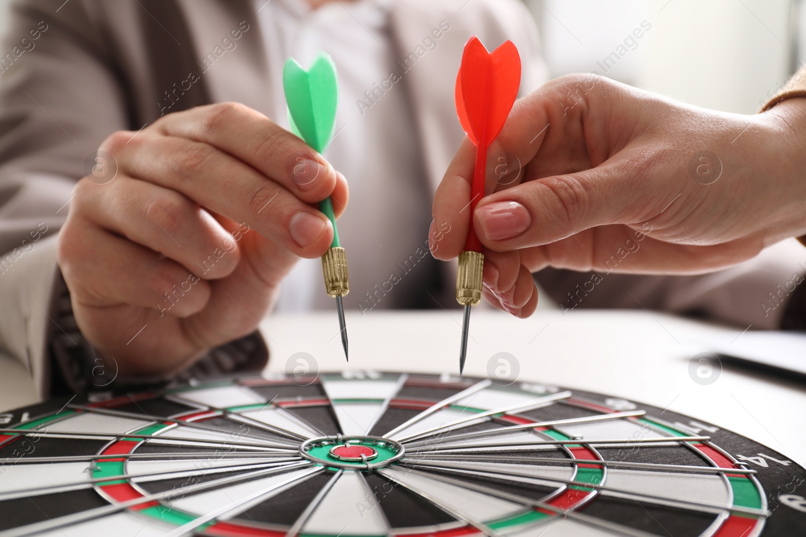 Photo of Business targeting concept. Man and woman with darts aiming at dartboard at table, closeup