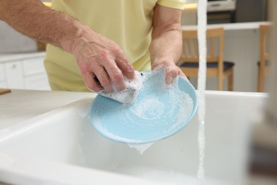 Photo of Closeup of man washing plate above sink in kitchen, view from outside