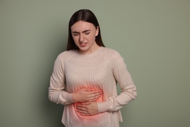 Woman suffering from abdominal pain on olive background