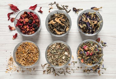 Flat lay composition with different dry teas on white wooden table