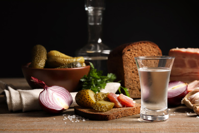 Photo of Cold Russian vodka with snacks on wooden table