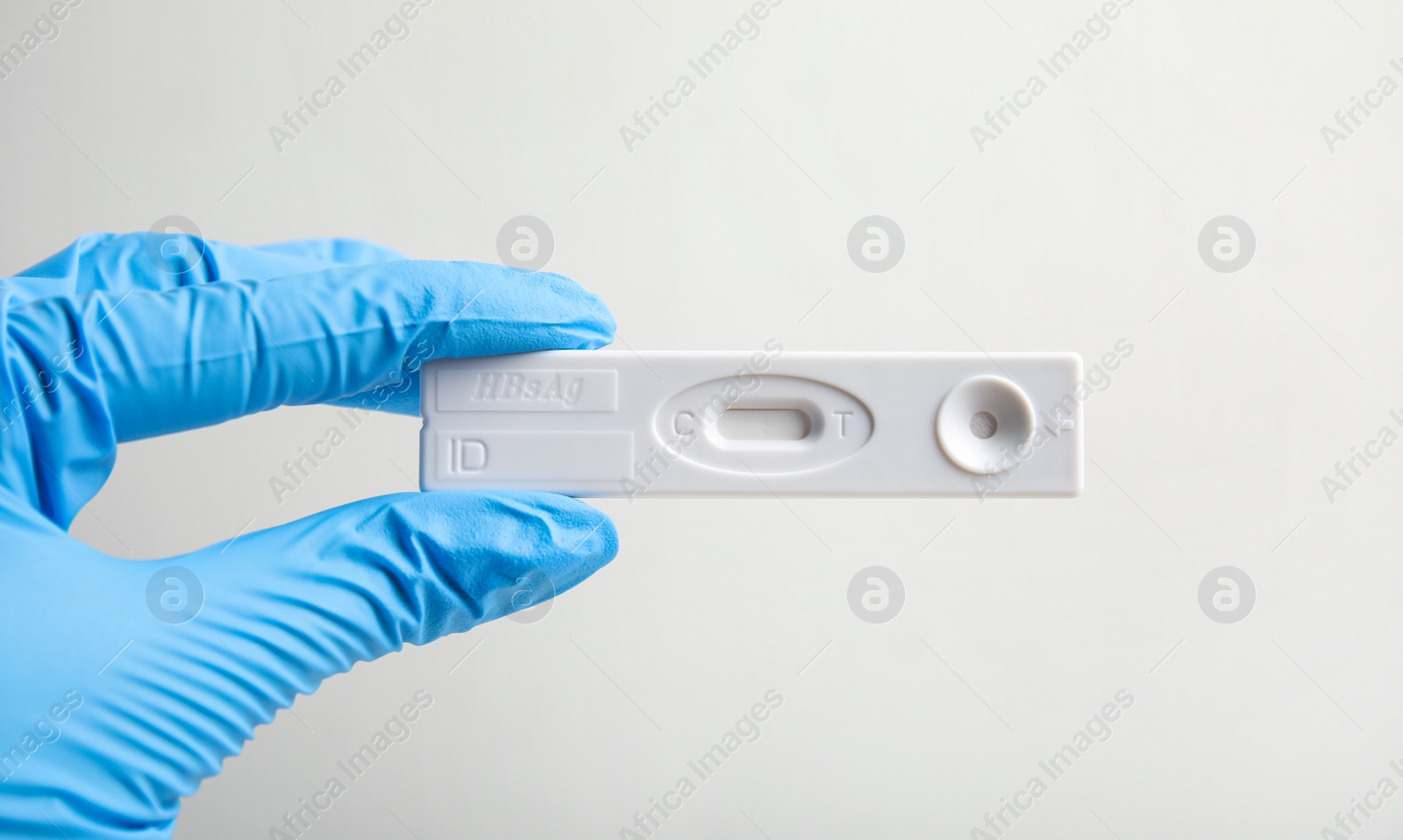 Photo of Doctor in gloves holding disposable express test for hepatitis on white background, closeup