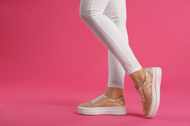 Woman wearing shoes on pink background, closeup. Space for text