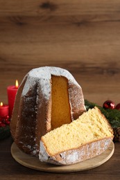 Photo of Delicious Pandoro cake with powdered sugar and Christmas decor on wooden table. Traditional Italian pastry